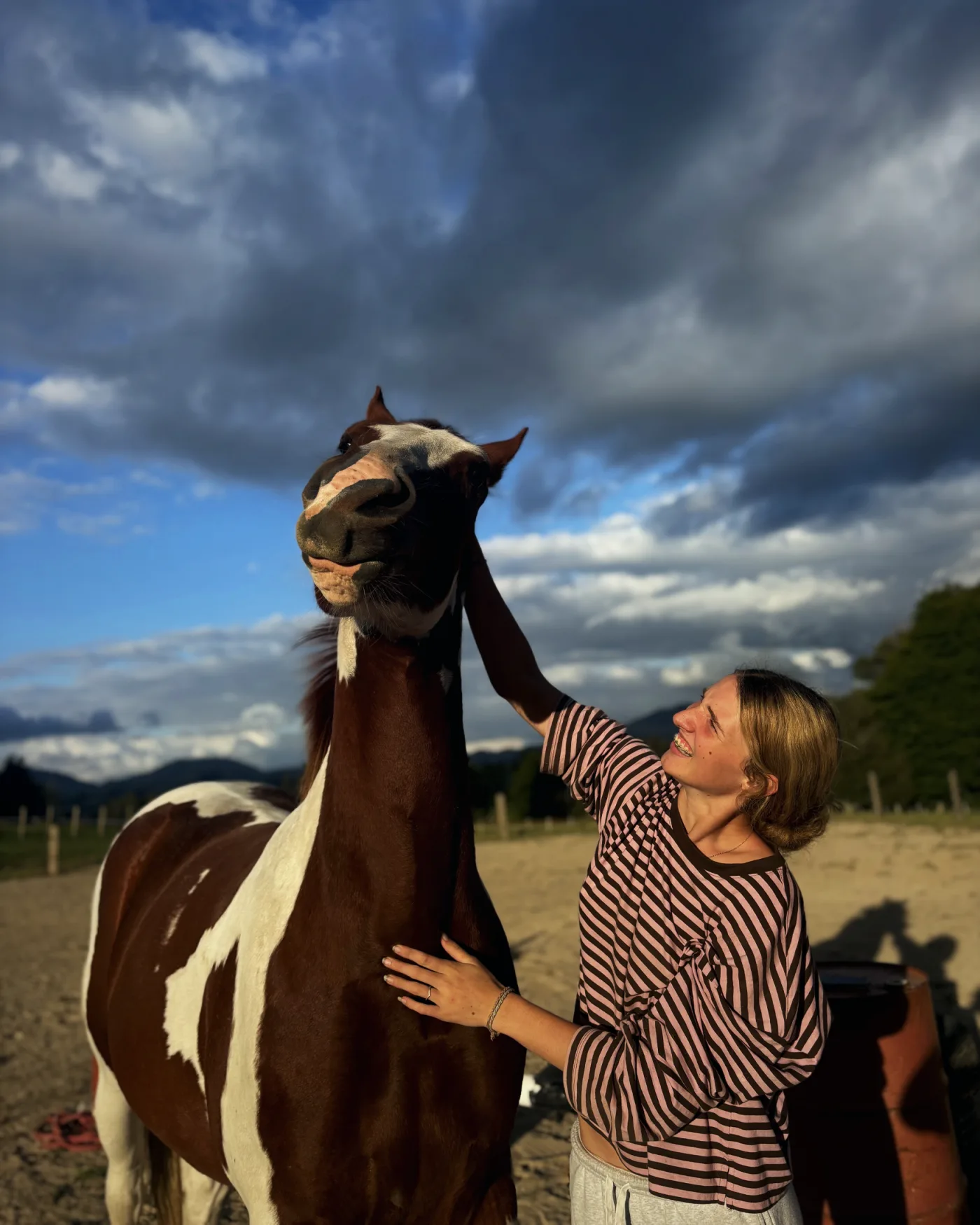 Jess Haskins with a paint horse under a dramatic sky